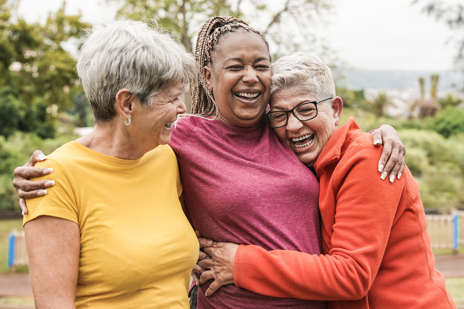 Three senior women laughing and hugging