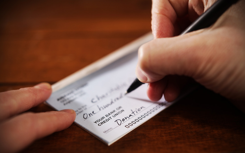 Closeup of a checkbook with someone writing a check.